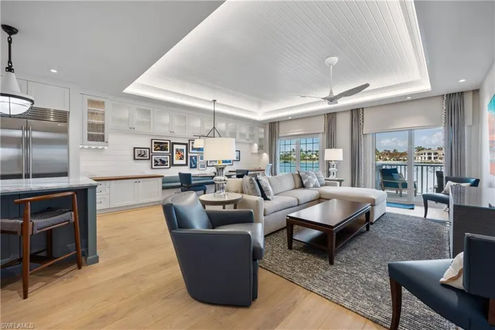 Living room featuring bay view, custom tray ceiling with lighting, engineered wood flooring, window treatments, and recessed lighting