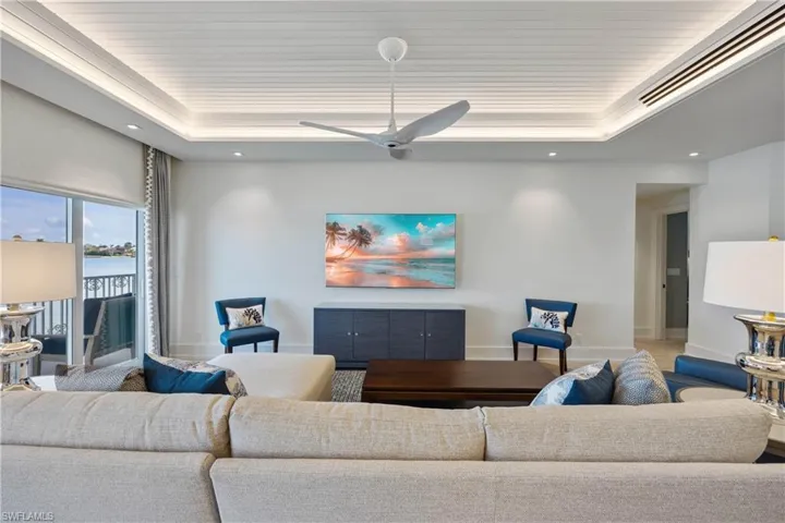 Living room featuring bay view, custom tray ceiling with lighting, modern HVAC vents, window treatments, and recessed lighting