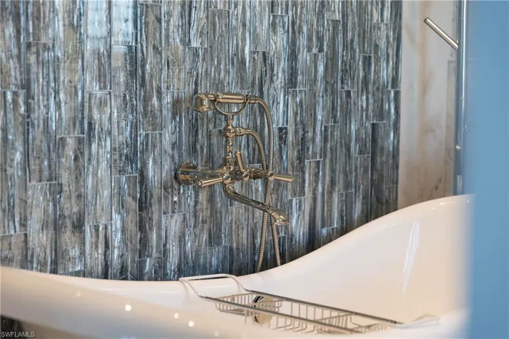 Primary suite bath view of freestanding soaking tub and waterfall tile design