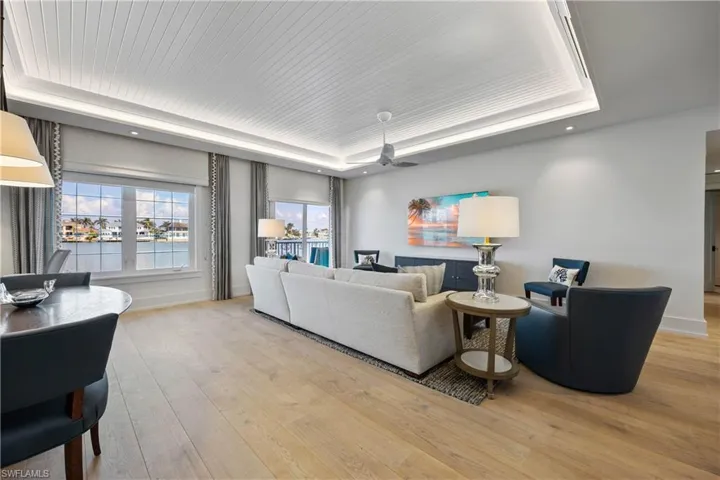 Living area featuring bay view, window treatments, custom tray ceiling with lighting, engineered wood floors, and recessed lighting