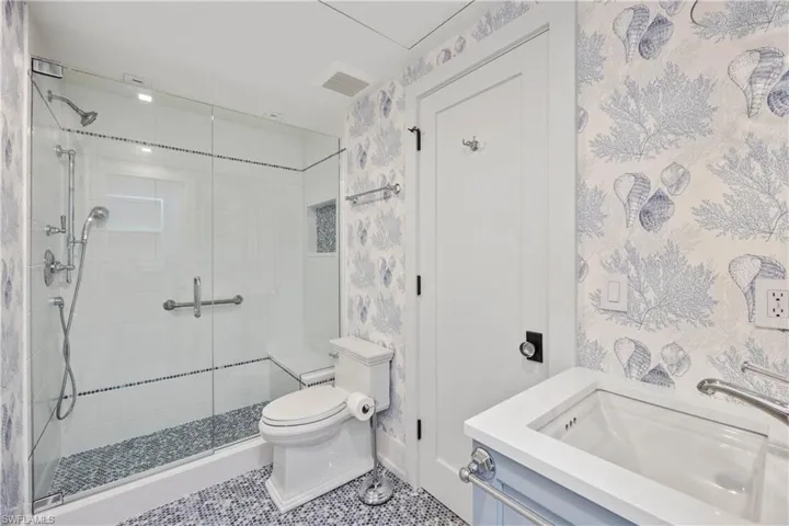 Hall bath featuring wallpaper, shower, and tile patterned flooring