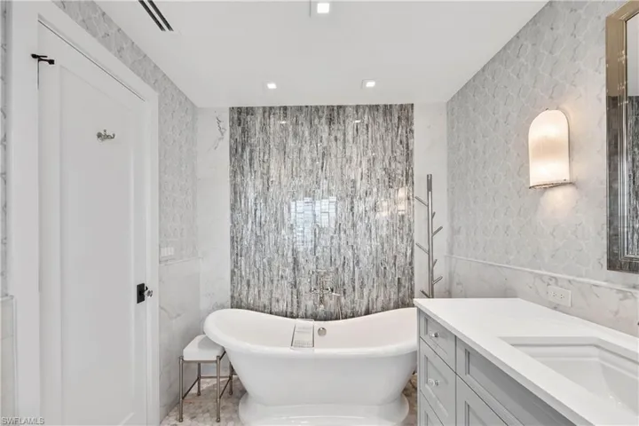 Primary suite bath featuring vanity, waterfall tile design, and a freestanding soaking tub