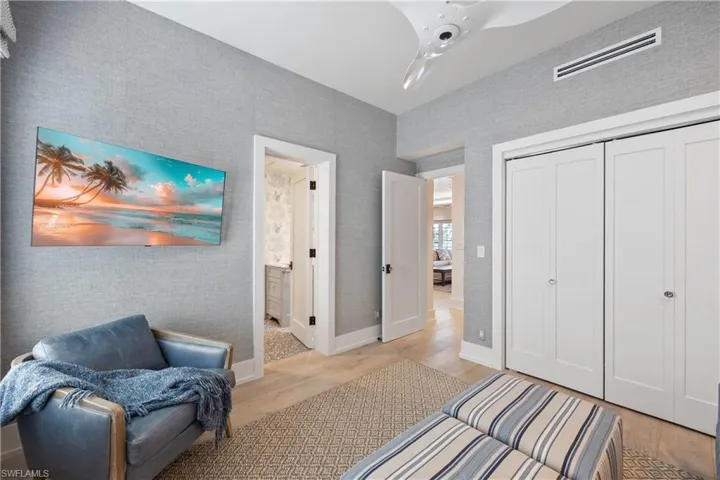 Guest bedroom three/den featuring engineered wood flooring and grasscloth wallpaper. View towards hall bath and living room