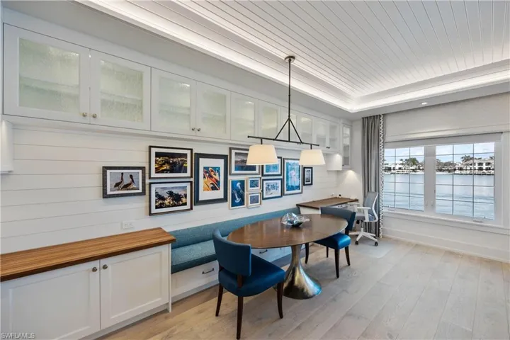 Dining space featuring banquette, bay view, shiplap, engineered wood flooring, window treatments, recessed lighting, and tray ceiling