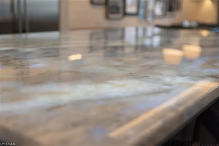 Kitchen featuring illuminated quartzite island countertop and custom cabinets with glass inserts