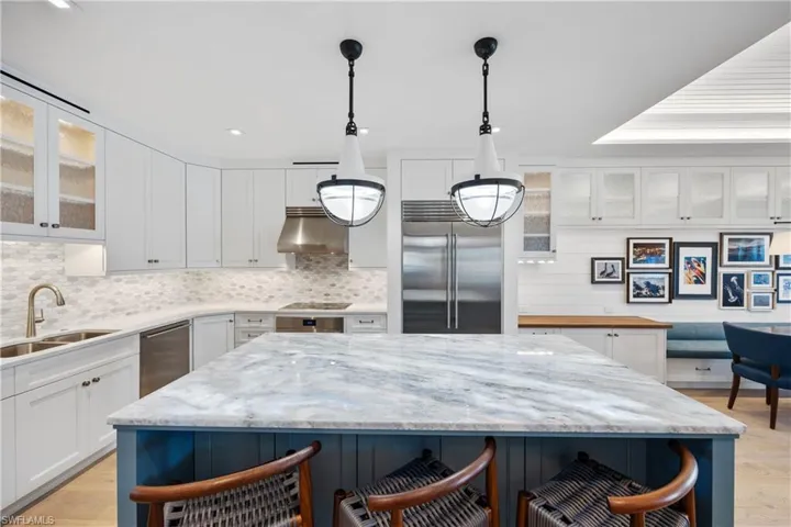 Kitchen featuring illuminated quartzite island countertop and custom cabinets with glass inserts