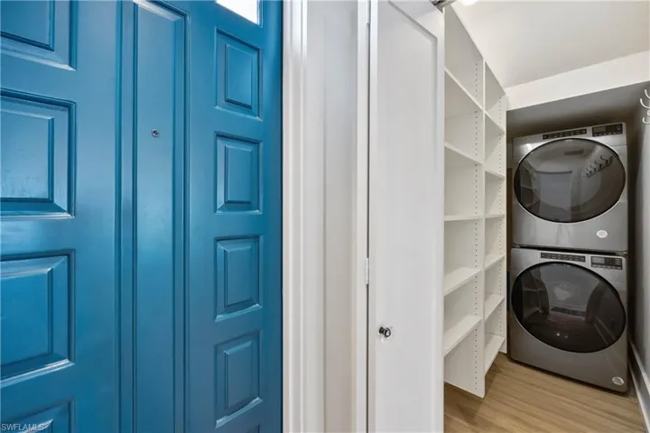 Laundry area with stacked washing machine and dryer, and engineered wood flooring