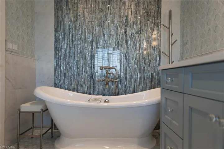 Primary suite bath with freestanding soaking tub and waterfall tile design