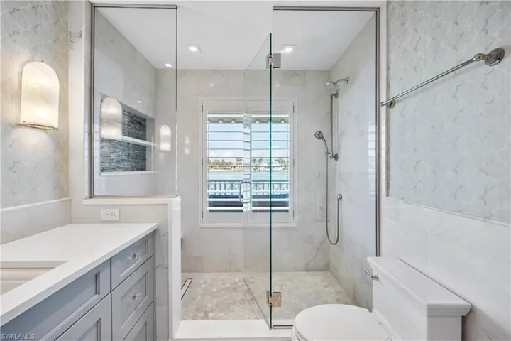 Primary suite bath featuring view of bay, vanity, and walk-in shower
