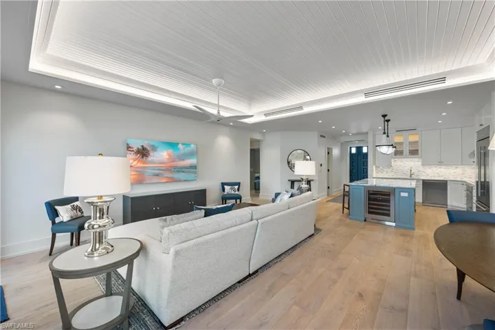 Living room featuring engineered wood flooring, custom tray ceiling with lighting, recessed lighting, Sub-Zero kitchen wine cooler