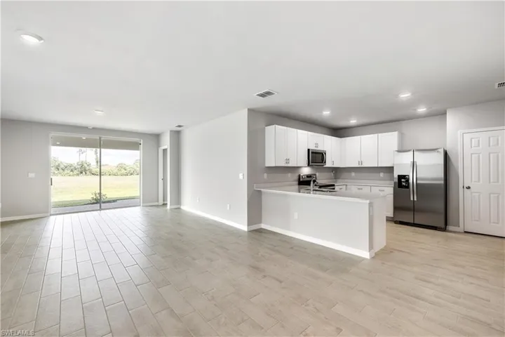 Kitchen featuring light hardwood / wood-style floors, kitchen peninsula, stainless steel appliances, white cabinets, and sink