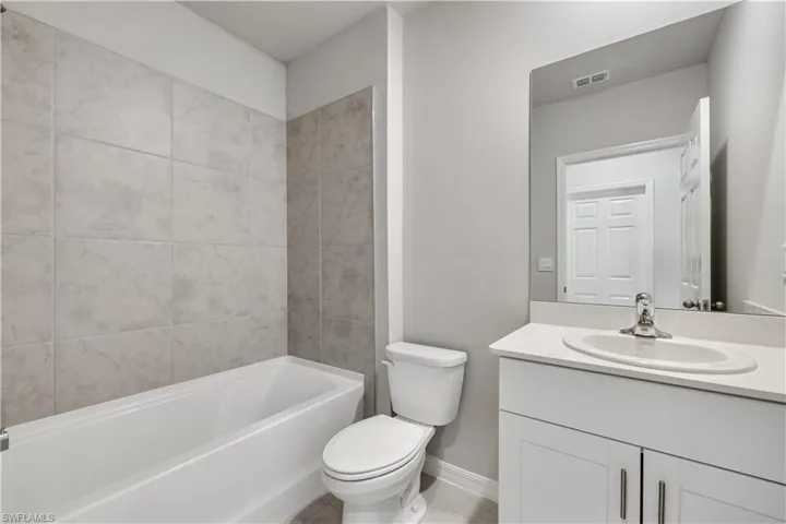 Full bathroom with tiled shower / bath, vanity, toilet, and tile flooring