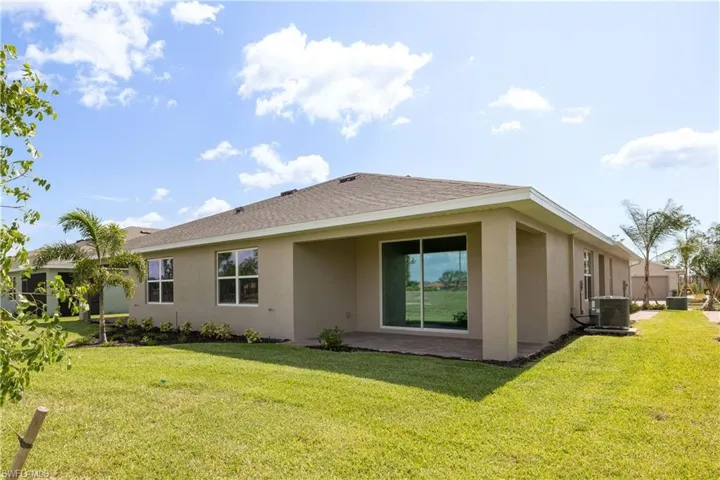 Back of property with central AC and a lawn