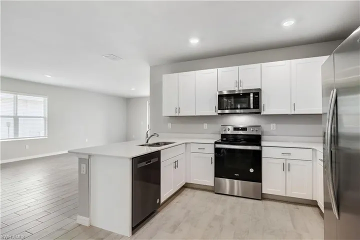 Kitchen featuring sink, light hardwood / wood-style floors, kitchen peninsula, and appliances with stainless steel finishes