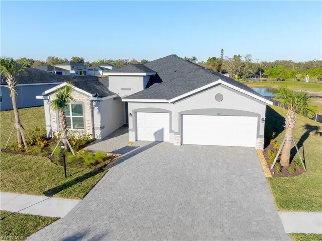 Single story home with a front yard, a garage, decorative driveway, and stucco siding