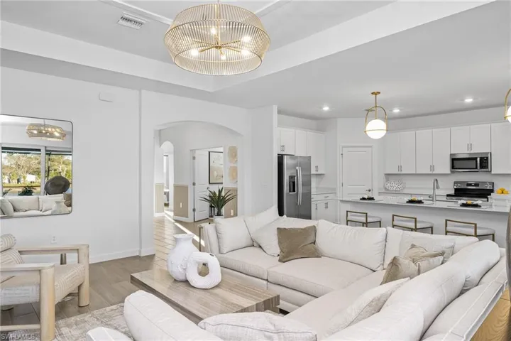 Living area featuring a chandelier, arched walkways, light wood-style flooring, and recessed lighting