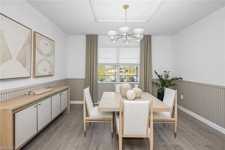 Dining area with wood tiled floors, a water view, a chandelier, and wainscoting