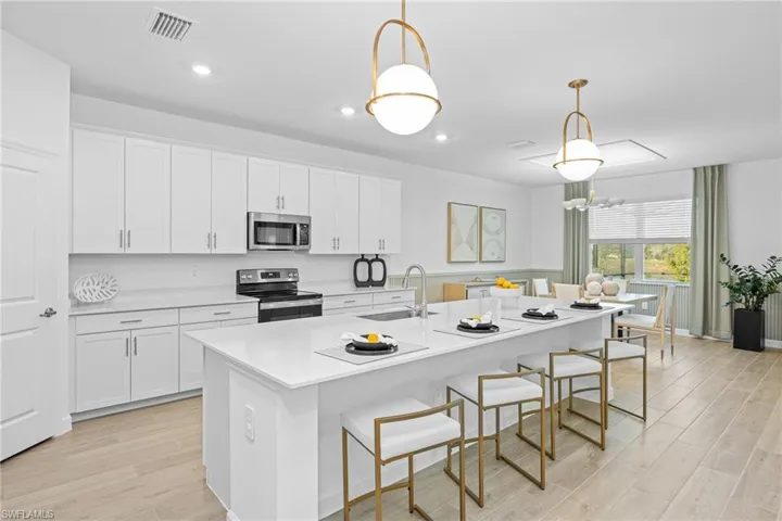 Kitchen featuring a breakfast bar, white cabinets, stainless steel appliances, pendant lighting, and light wood finished floors