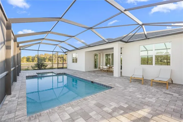 Outdoor pool featuring a sunroom, a patio, and glass enclosure