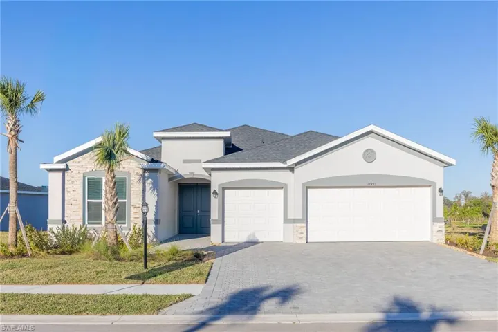 View of front facade with decorative driveway, an attached garage, stucco siding, a shingled roof, and a front lawn
