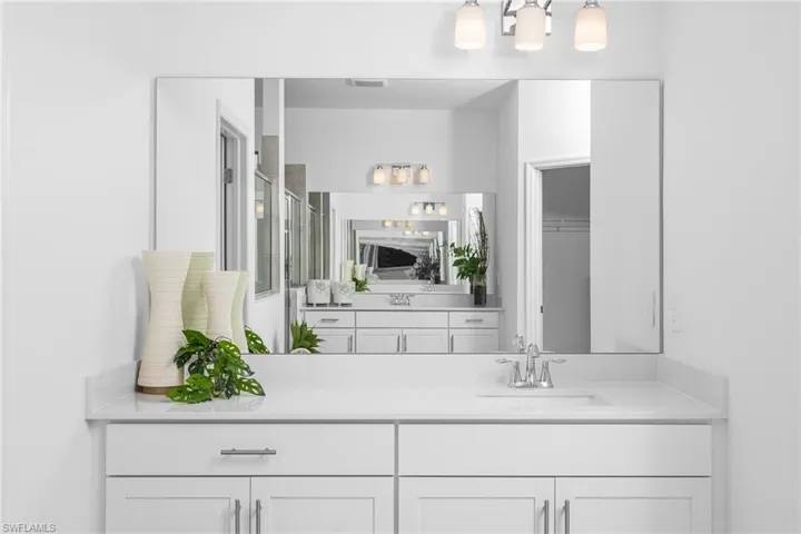 Full bath with a shower stall, vanity, and a closet