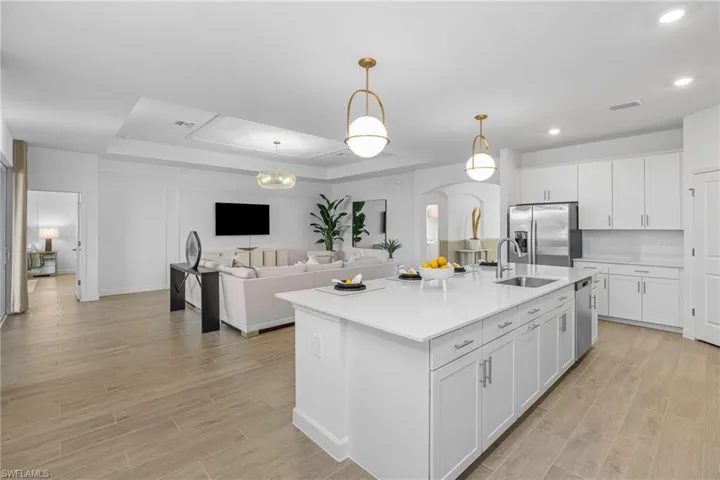 Kitchen with a tray ceiling, arched walkways, white cabinetry, open floor plan, and recessed lighting