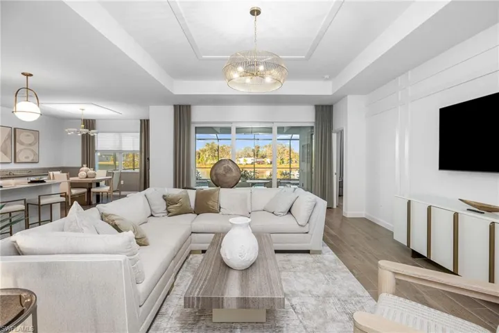 Living area featuring a chandelier, a raised ceiling, and plenty of natural light