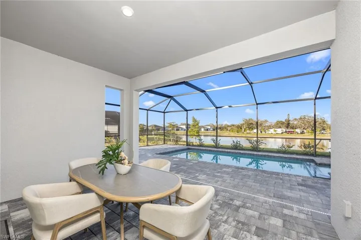 Swimming pool with a sunroom, a lanai, a water view, a patio, and outdoor dining space