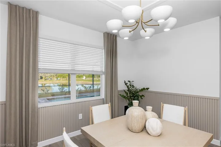 Dining room featuring wood finished floors, a chandelier, wainscoting, and a water view