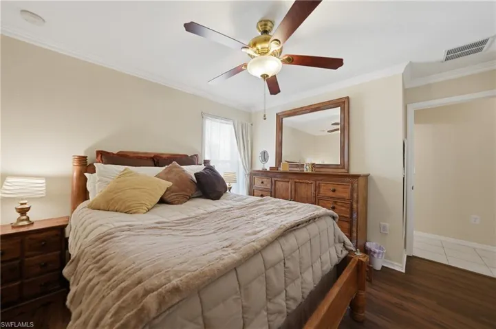 Bedroom featuring ornamental molding, a ceiling fan, and dark wood-type flooring
