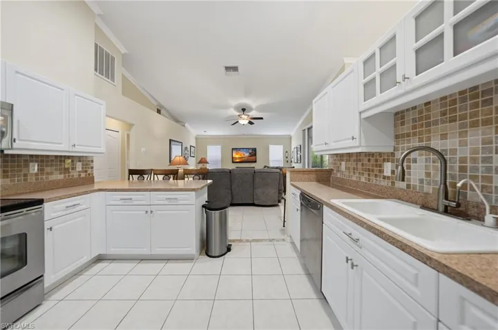 Kitchen with backsplash, open floor plan, crown molding, a peninsula, and glass insert cabinets