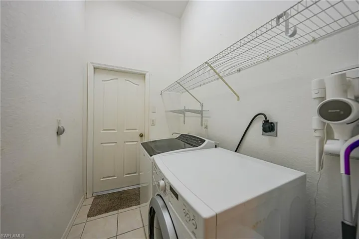 Laundry area featuring a textured wall, washing machine and dryer, and light tile patterned floors