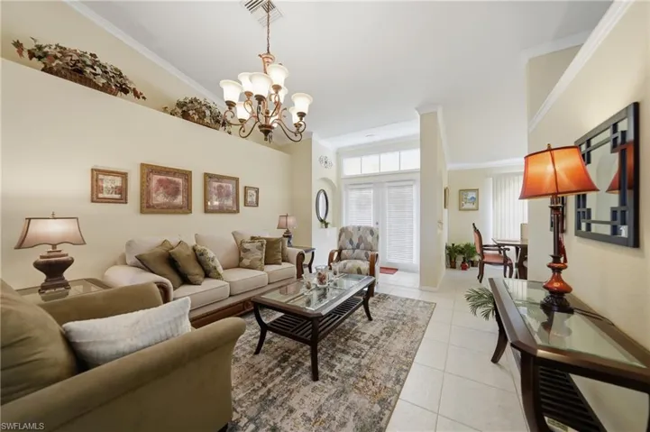 Living area with crown molding, hanging lights, and light tile patterned floors