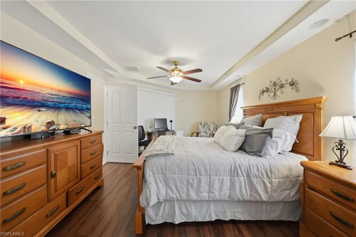 Bedroom featuring a raised ceiling, dark wood finished floors, and ceiling fan