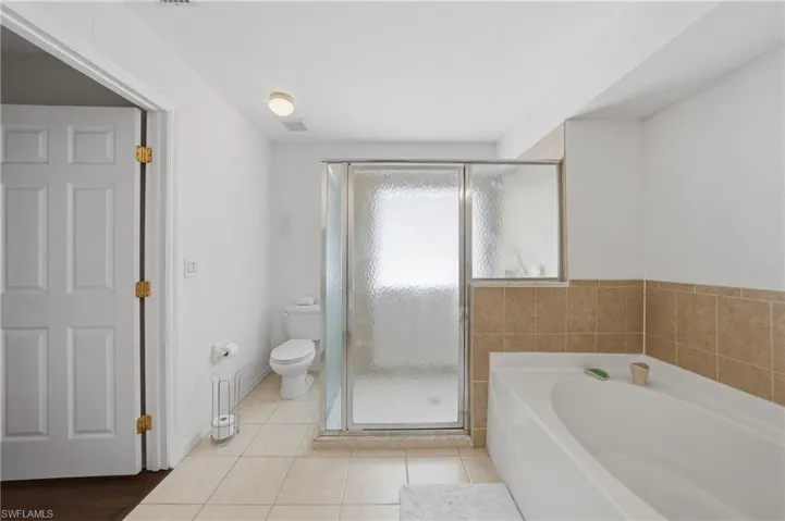Full bath featuring a bath, a stall shower, and light tile patterned floors