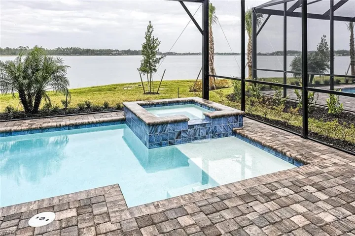 View of swimming pool featuring a water view, a pool with connected hot tub, and a lanai