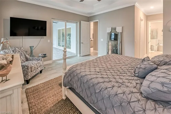 Bedroom featuring a ceiling fan, baseboards, access to exterior, ensuite bath, and crown molding