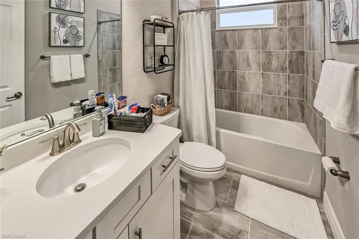 Bathroom featuring toilet, shower / bath combo with shower curtain, and vanity
