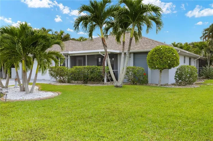 View of front facade featuring a front yard, roof with shingles, stucco siding, and a sunroom