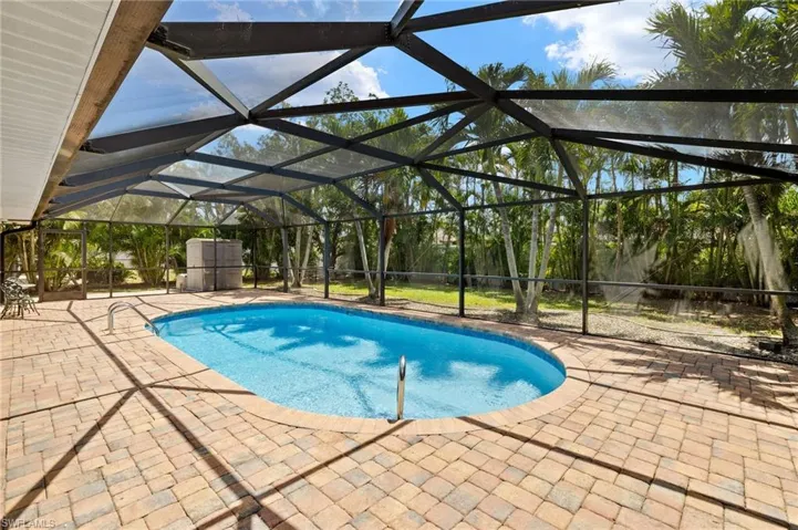 Outdoor HEATED pool featuring a lanai and a patio area