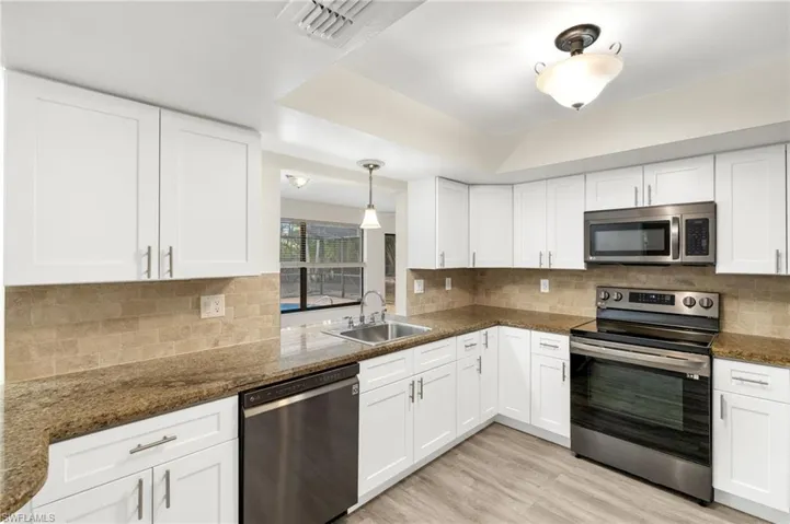 Kitchen with a sink, white cabinets, and appliances with stainless steel finishes