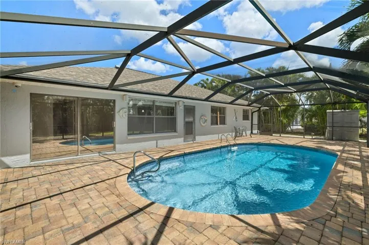 Outdoor HEATED pool with a patio area and glass enclosure