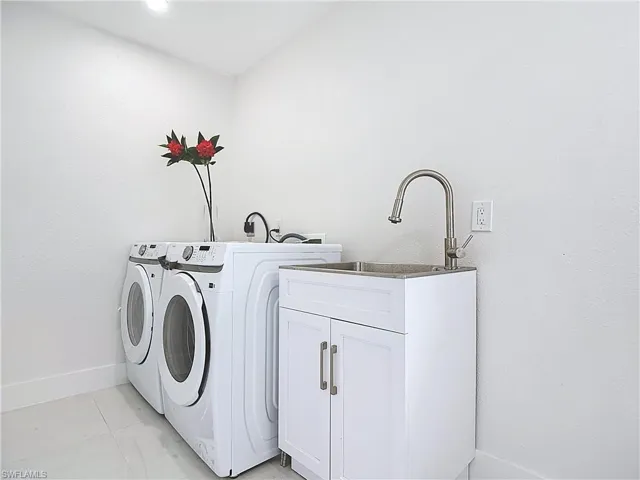 Laundry room featuring washer and clothes dryer, cabinet space, and baseboards