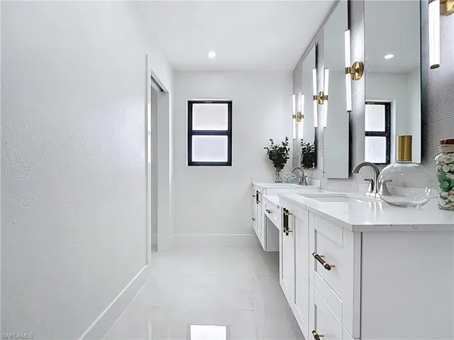 Bathroom featuring baseboards, double vanity, and tile patterned flooring