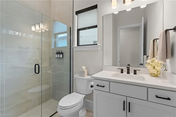 Full bath with baseboards, a stall shower, toilet, and vanity