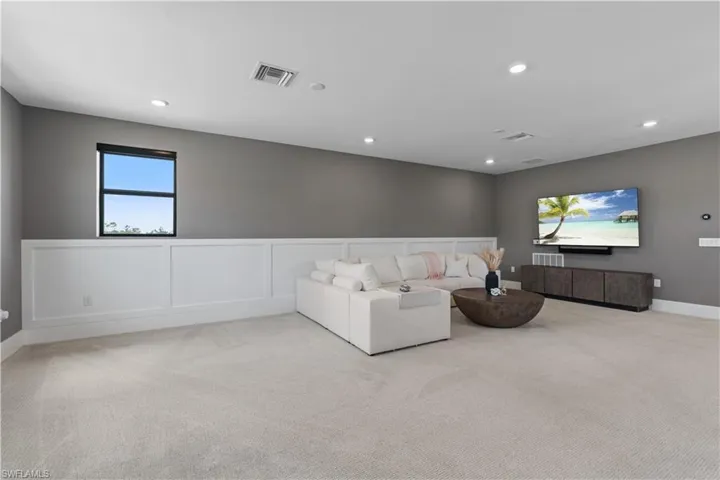 Living area featuring carpet flooring, recessed lighting, a wainscoted wall, and baseboards