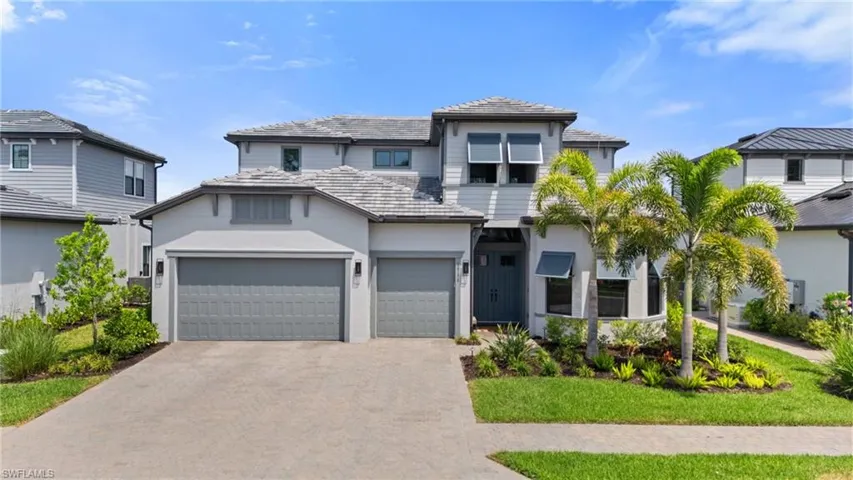 View of front of property featuring aphalt driveway, stucco siding, a tile roof, and an attached garage