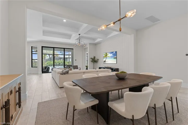 Dining room featuring coffered ceiling, beamed ceiling, baseboards, visible vents, and a notable chandelier