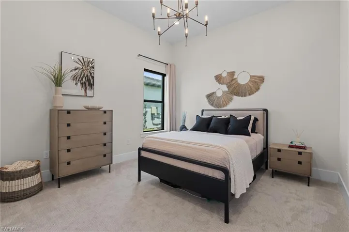 Bedroom with baseboards, a notable chandelier, and carpet flooring