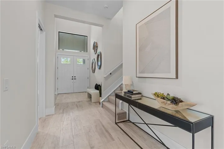 Entrance foyer featuring light wood finished floors, stairway, and baseboards